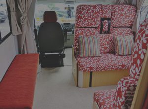 Motorhome refurbished seating area with red and white floral and striped throw cushions, plain red benchseat