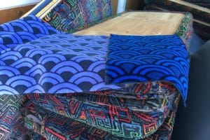 Stack of dismantled bus seats with new fabric draped over the top waiting to be refurbished