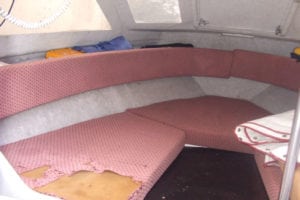 Marine interior before refurbishment with pink ripped upholstery showing foam underneath