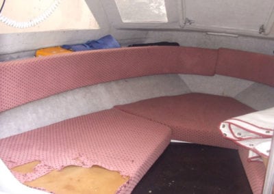 Marine interior before refurbishment with pink ripped upholstery showing foam underneath