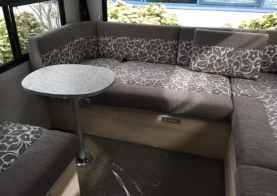 Motorhome interior seating area upholstered in brown and white floral pattern with solid brown accent