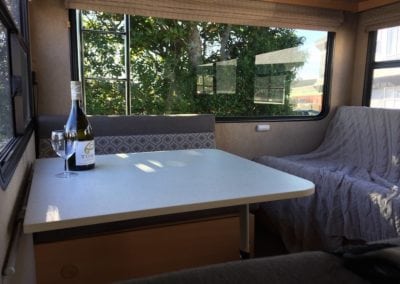 Finished interior of motorhome with eating and bedding areas upholstered in a soft grey with pattered geometric grey and white accent