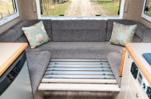 Motorhome seating area converted into slat bedding, upholstered in grey fabric