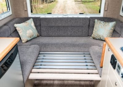 Motorhome seating area converted into slat bedding, upholstered in grey fabric