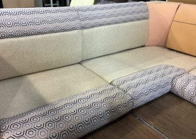 Motorhome corner seating in factory, with semi - completed upholstery in beige base colour with black and grey geometric patterned accent