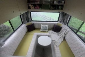 6 berth motorhome interior upholstered in yellow with a grey, pink and white geometric patterned accent fabric