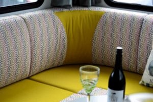 Motorhome seating area with a yellow squabs and seat backs upholstery accented with a grey, yellow, pink and white geometric pattern