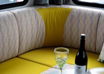 Motorhome seating area with a yellow squabs and seat backs upholstery accented with a grey, yellow, pink and white geometric pattern