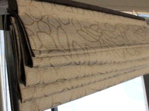 Roman blind close up, beige coloured with gold leaf pattern in drawn up position