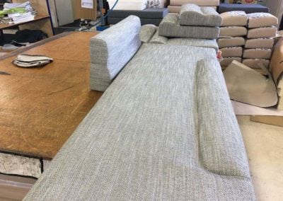 Upholstery workbench with large cushion in foreground and smaller finished cushions in background