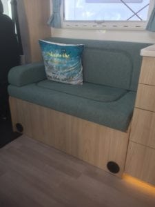 Passenger seating in motorhome with moulded foam, trimmed in sea green, with a blue, white and gold throw cushion