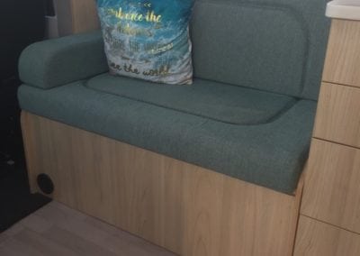 Passenger seating in motorhome with moulded foam, trimmed in sea green, with a blue, white and gold throw cushion