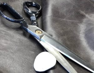 Tailors scissors and chalk on a piece of black leather