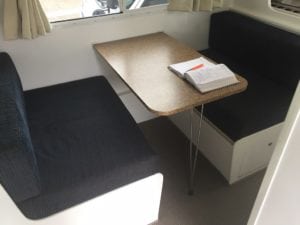 Dinette seating trimmed in dark brown before refurbishment. A brown table sits in the middle of each seat.