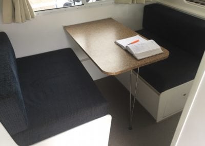 Dinette seating trimmed in dark brown before refurbishment. A brown table sits in the middle of each seat.