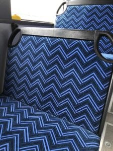 City Rider bus seat trimmed in blue chevron pattern. In bus with window in background