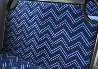 City Rider bus seat trimmed in blue chevron pattern. In bus with window in background