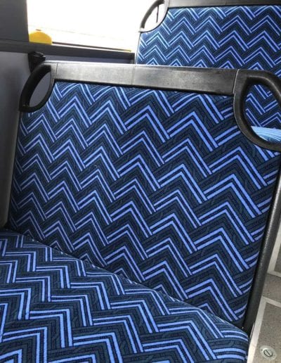 City Rider bus seat trimmed in blue chevron pattern. In bus with window in background