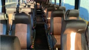 Rows of double bus seats on either side of aisle upholstered in chocolate and tan leather
