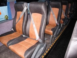 Four rows of tan and chocolate leather upholstered seat in bus.