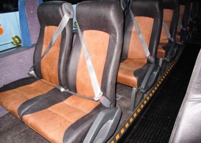 Four rows of tan and chocolate leather upholstered seat in bus.