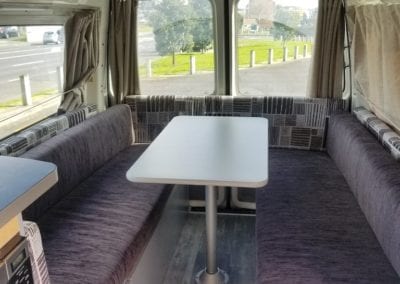 2 berth walk through motorhome lounge upholstered in chocolate brown fabric with a geometric accent used for the side cushions