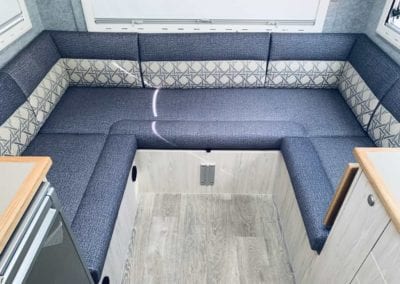 Motorhome lounge upholstered in blue with a white and blue geometric accent on the seat back