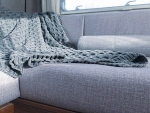 6 berth motorhome lounge after refurbishment, trimmed in grey . Cable knit throw is draped over the cushions.