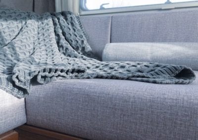 6 berth motorhome lounge after refurbishment, trimmed in grey . Cable knit throw is draped over the cushions.