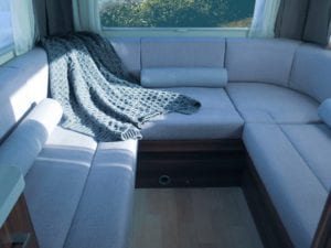 Soft furnishings of grey motorhome lounge cushion with luxury throw draped over cushions.