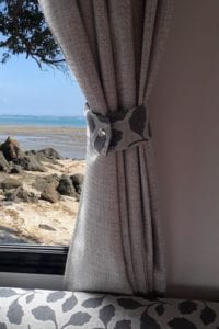 Grey curtain with floral tie above grey floral motorhome lounge.