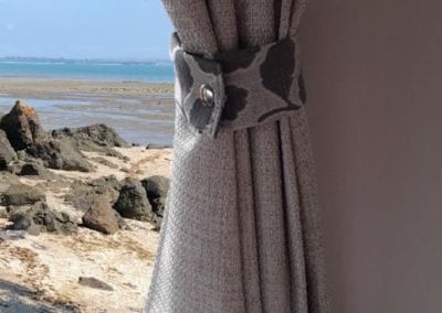 Grey curtain with floral tie above grey floral motorhome lounge.