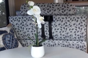 Dinette upholstered in grey floral sits behind table with orchid in a pot