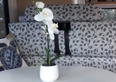 Dinette upholstered in grey floral sits behind table with orchid in a pot