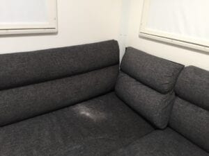 Corner of lounge with dark grey squabs and back cushions.