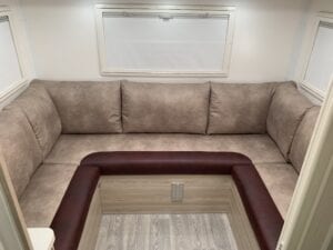 Refurbished U shaped motorhome lounge in two tone brown and burgundy.