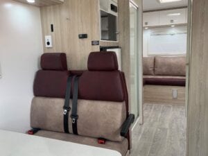 Brown and burgundy dinette seating in foreground with part of lounge seating visible through doorway in background.