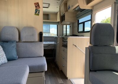Motorhome seating to left and right of cabin with new upholstery in light grey.