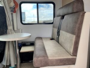 Two tone brown and beige dinette seat with small round table and window in the background