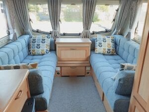 Caravan lounge in grey upholstery with throw cushions and window in background