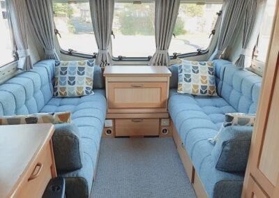 Caravan lounge in grey upholstery with throw cushions and window in background